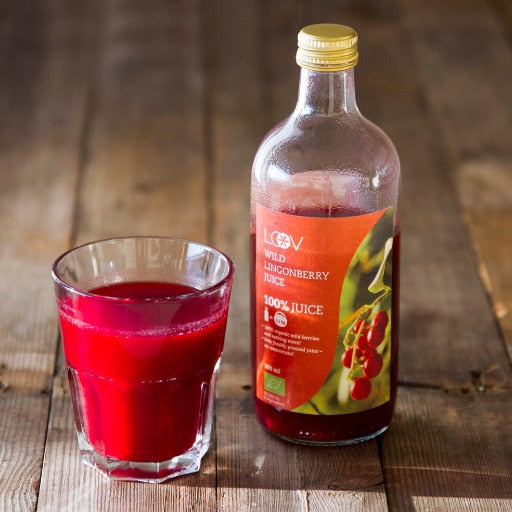 A glass filled with lingonberry juice and a bottle of lingonberry juice