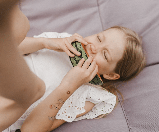 young girl biting into a slice of watermelon